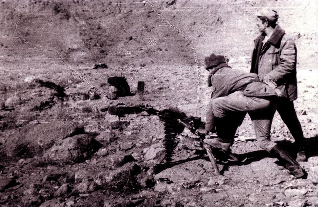 Sovětské jednotky v Afghánistánu. Hory poblíž Kábulu, 1986. Důstojník 40. armády (OKSVA) provádí palebný výcvik s jednotkami, které dorazily ze Sovětského svazu, a bombarduje je 30 mm automatickým granátometem AGS-17 „Flame“ (tzv. „zkušební provoz“ pro osvědčení se v boji). Jednotky jsou v krytech. Vlastní naskenovaná fotografie E. Kuvakin. Zdroj: Wikimedia Commons